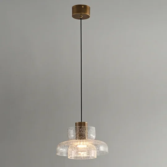 Cracked glass pendant light with brass hardware hanging over a kitchen island